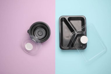Pastel arka planda tek kullanımlık siyah plastik yiyecek kapları. Üst görünüm