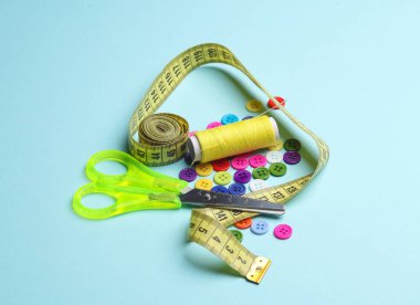 Tüylü makas, şerit ve iğne ölçümü, mavi arkaplanda düğmeler. Aksesuarlar dikiliyor.