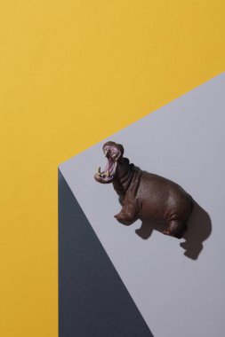 Toy hypopotamus on the corner of gray cube. Optical geometric illusion. Creative layout. Minimalism clipart