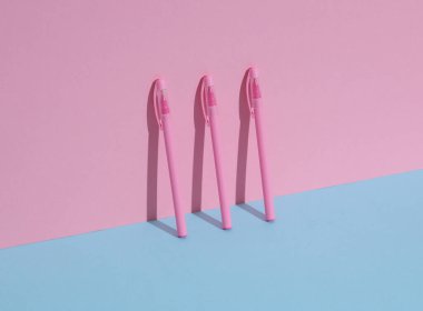 Mavi-pembe arka planda plastik pembe kalemler. İş konsepti. Yaratıcı düzen, minimalizm