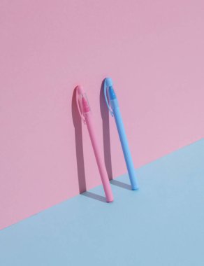 Mavi-pembe arka planda plastik pembe ve mavi kalemler. İş, eğitim kavramı. Yaratıcı düzen, minimalizm