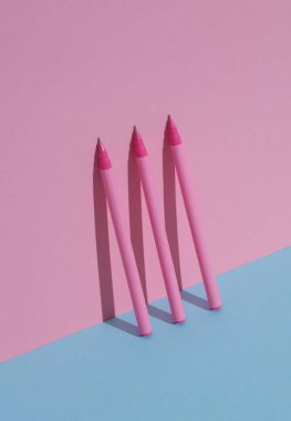 Mavi-pembe pastel arka planda plastik pembe kalemler. İş, eğitim kavramı. Yaratıcı düzen, minimalizm