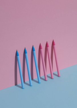 Mavi-pembe pastel arka planda plastik pembe ve mavi kalemler. İş, eğitim kavramı. Yaratıcı düzen, minimalizm