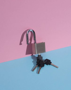 Mavi-pembe arka planda anahtarı olan metal açık kilit. Minimalizm kompozisyonu. Yaratıcı yerleşim