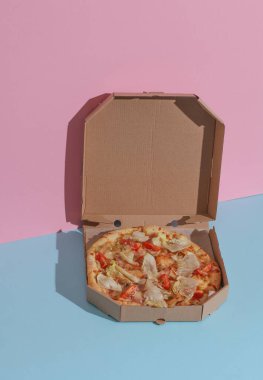 Mavi-pembe arka planda bir kutu pizzayı aç. Moda yemek fotoğrafı.
