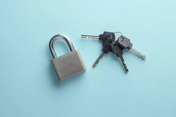 Closed metal lock with keys on a blue background