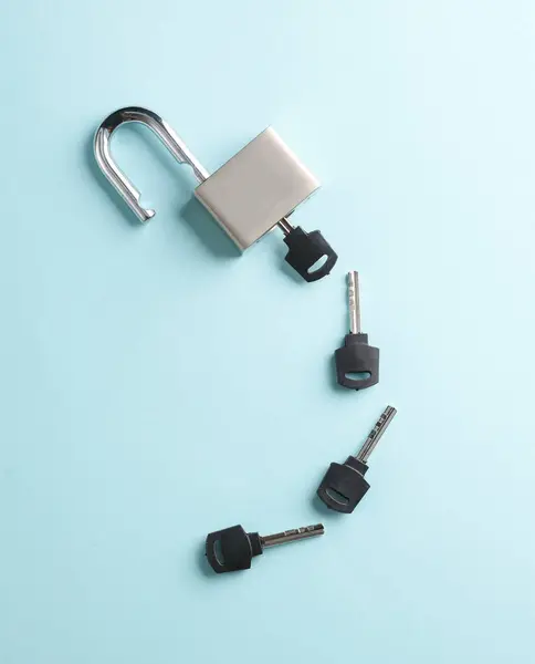 Opened metal lock with keys on a blue background