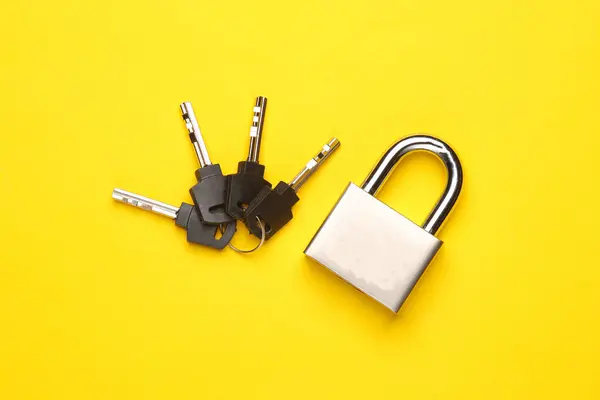 Metal lock with keys on yellow background