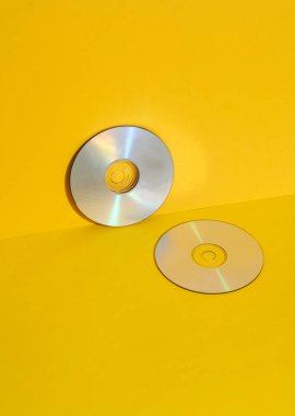 Sarı arka planda CD 'ler. Retro 80 'ler. Modası geçmiş teknoloji. Yaratıcı düzen, minimalizm, modaya uygun durgun yaşam