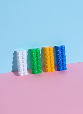 Oyuncak tuğla yapımcısı pembe mavi arka planda. Yaratıcı yerleşim
