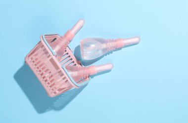 Mavi arka planda üç vajinal lavman bulunan bir süpermarket sepeti. Kadın Sağlığı