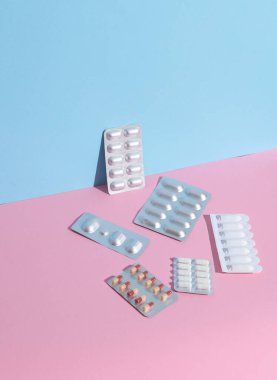 Çeşitli ilaçlar, mavi-pembe arka planda su toplayan haplar. Yaratıcı düzen, minimalizm tıp konsepti