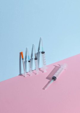 Mavi-pembe renkli arka planda farklı tıbbi şırıngalar. Minimalizm tıbbi düzeni
