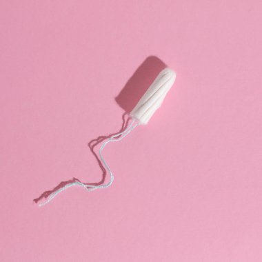 Pembe arka planda gölgeli bir tampon. Kadın hijyeni. Kritik adet günleri. Minimalizm.
