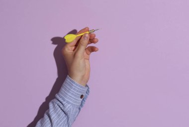 Adamın eli gömleğinde mor pastel arka planda gölgeli dart okunu tutuyor. İş konsepti