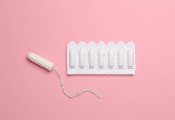 Women's health, treatment of women's diseases. Vaginal suppositories and tampon on pink background. Flat lay