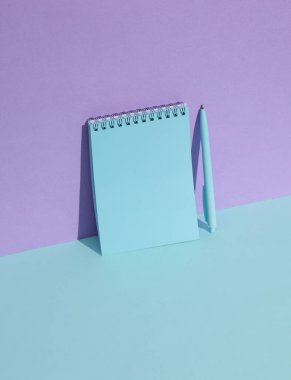 Pastel arka planda kalem olan mavi defter. Yaratıcı yerleşim