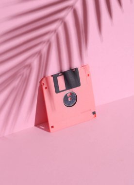 Pembe arka planda palmiye yaprağı gölgesi olan disket. Minimalizm. Retro 80 'lerin yaratıcı düzeni