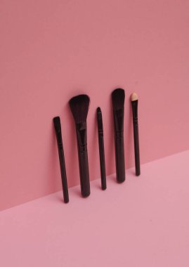 Pembe arka planda siyah makyaj fırçaları. Yaratıcı güzellik düzeni.