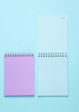 Mavi pastel arka plan üzerine iki defter. Minimalizm. Yaratıcı yerleşim