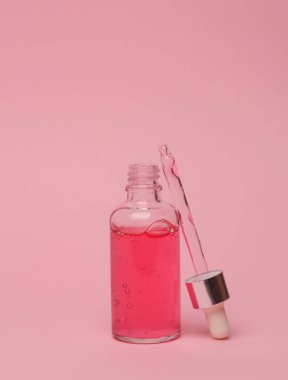 Pembe arka planda pipeti olan serum şişesi. Güzellik konsepti