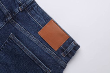 Beyaz arka planda deri etiketli mavi kot pantolon