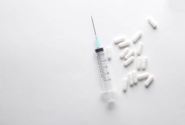 beyaz zemin üzerine haplarla şırınga