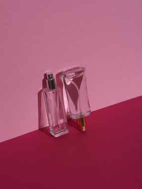 Pembe arka planda, gölgeli parfüm şişeleri. Güzellik konsepti. Yaratıcı düzen, minimalizm