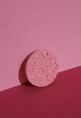 Pembe arka planda gölgeli bir makyaj süngeri. Güzellik konsepti. Yaratıcı düzen, minimalizm