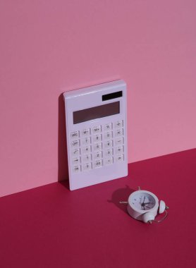 Pembe arka planda çalar saati olan bir hesap makinesi. Minimalizm iş konsepti