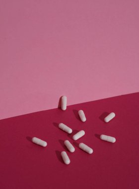 Pembe arka planda beyaz haplar, gölgeli. Minimalizm, tıp düzeni