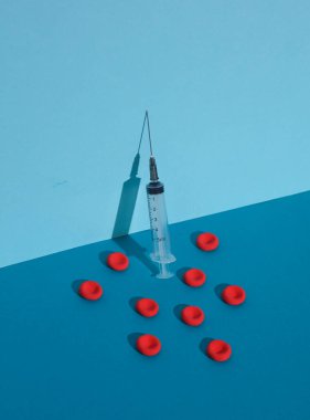 Syringe and Red blood cells on blue background. Medicine concept. Creative layout clipart