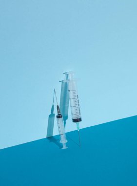 Mavi arka planda, gölgeli şırıngalar. Yaratıcı yerleşim