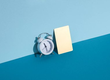 Mavi arka planda çalar saati olan altın kartvizit. Yaratıcı iş düzeni