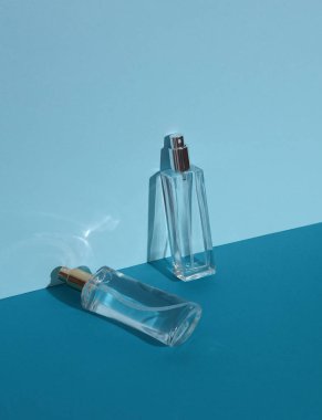 Mavi arka planda gölgeli parfüm şişeleri. Güzellik konsepti. Yaratıcı düzen, minimalizm