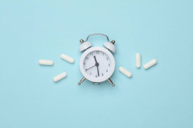 Mavi arka planda çalar saati olan haplar. Üst görünüm