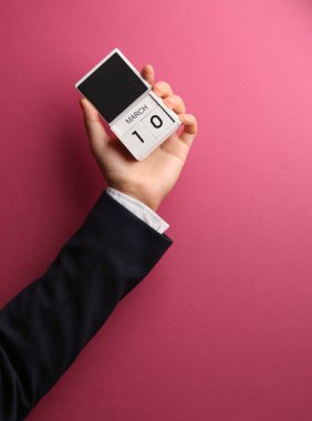 10 Mart tahta blok takvimi Pembe arka planda erkek eli