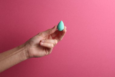 Pembe arka planda kadın elinde makyaj süngeri blenderi