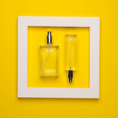 Sarı arka planda beyaz çerçeveli parfüm şişeleri. Yaratıcı düzen. Minimalizm