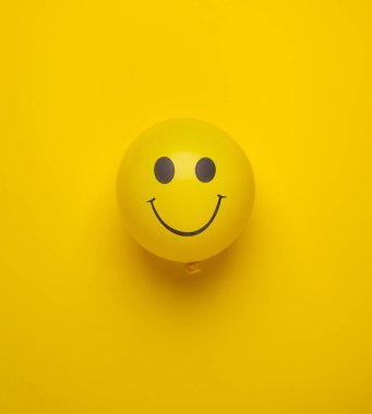 Sarı arka planda gülen yüzlü balon. Yaratıcı düzen. Minimalizm