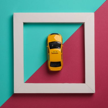 Pembe arka planda beyaz çerçeveli oyuncak taksi arabası. Yaratıcı düzen. Minimalizm