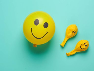 Mavi arka planda gülen yüzlü sarı balon. Yaratıcı düzen. Minimalizm