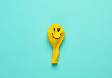 Mavi arka planda gülen yüzlü sarı balon. Yaratıcı düzen. Minimalizm