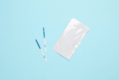 Mavi arka planda hamilelik testinin iki şeridi. Hamileliğin teyidi