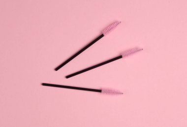 Pembe arka planda kirpikleri taramak için fırçalar. Güzellik konsepti