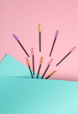 Pembe mavi arka planda kirpikleri taramak için fırçalar. Güzellik konsepti