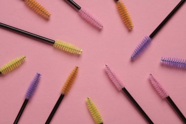 Pembe arka planda kirpikleri taramak için fırçalar. Güzellik konsepti