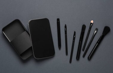 Siyah makyaj fırçaları ve siyah arka planda metal kutular. Güzellik konsepti