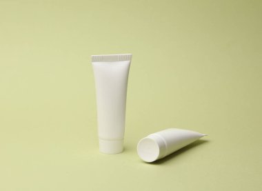 Yeşil arka planda beyaz krema tüpleri. Tasarım şablonu, model. Güzellik konsepti