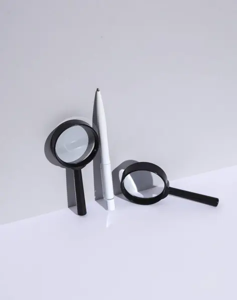 stock image White pen and magnifying glasses on white background with shadow. Creative layout. Minimal business concept. Conceptual still life